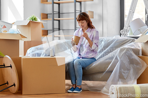 Image of happy woman moving to new home and eating wok