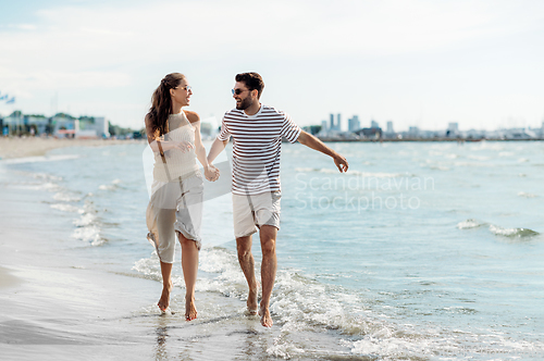 Image of happy couple running along summer beach