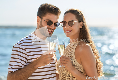 Image of happy couple drinking champagne on summer beach