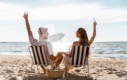 Image of happy couple drinking champagne on summer beach