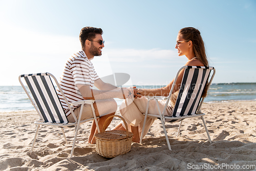 Image of happy couple sitting in folding chairs on beach