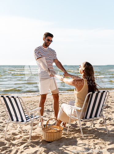 Image of happy couple sitting in folding chairs on beach