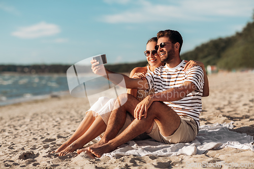 Image of happy couple taking selfie by smartphone on beach