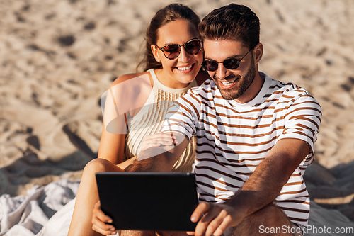 Image of happy couple with tablet pc at on summer beach