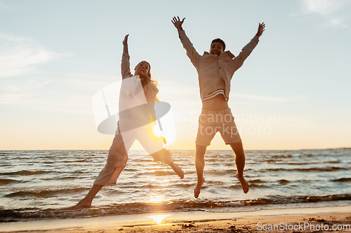 Image of happy couple jumping on summer beach