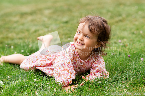 Image of happy little baby girl lying on grass in summer