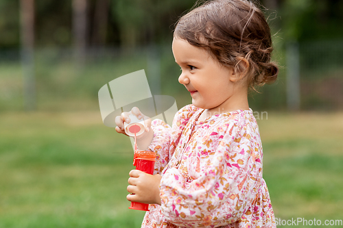 Image of happy baby girl with soap bubble blower in summer