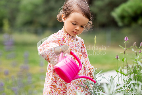 Image of happy baby girl with watering can in summer garden