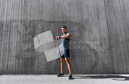 Image of young man with fitness tracker on city street