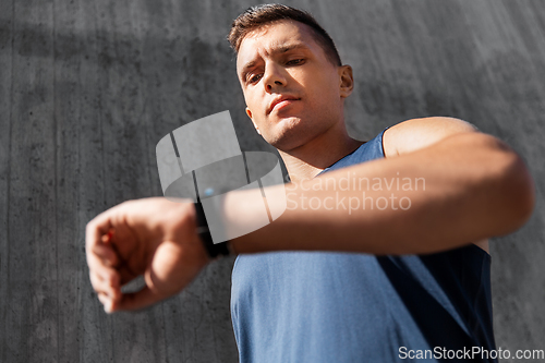 Image of young man with fitness tracker on city street