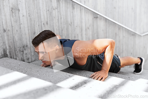 Image of young man doing push ups on stairs outdoors