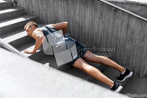 Image of young man doing push ups on stairs outdoors