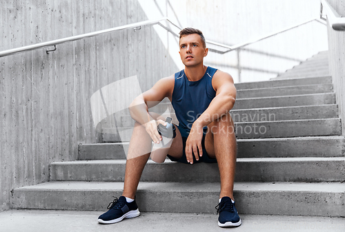 Image of sportsman with shake in bottle sitting on stairs