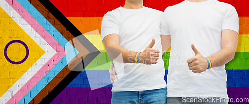 Image of close up of male gay couple over pride flag