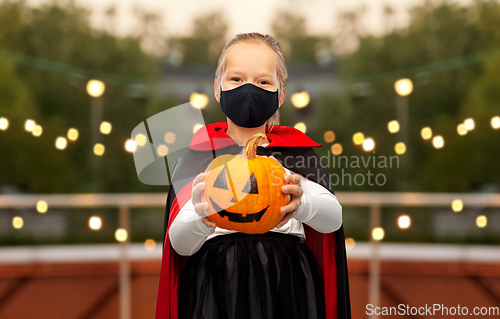 Image of girl in halloween costume and mask with pumpkin