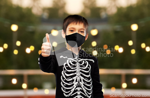 Image of boy in mask and halloween costume shows thumbs up