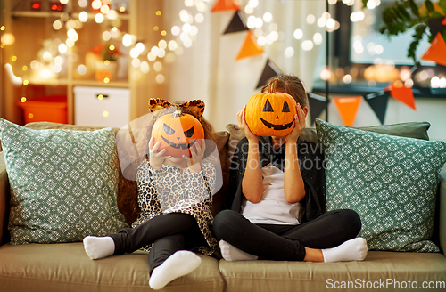 Image of girls in halloween costumes with pumpkins at home