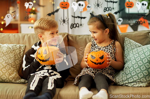 Image of kids in halloween costumes with pumpkins at home