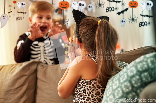 Image of kids in halloween costumes having fun at home