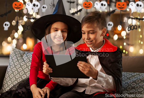 Image of kids in halloween costumes with tablet pc at home