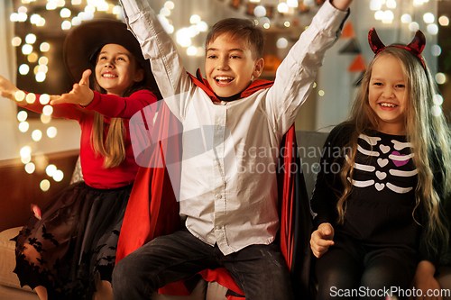 Image of kids in halloween costumes s having fun at home