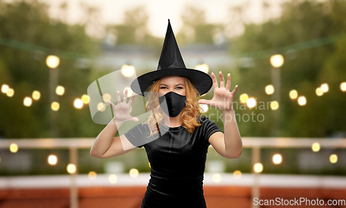 Image of woman in black mask and halloween costume of witch
