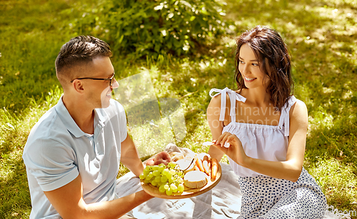 Image of happy couple having picnic at summer park