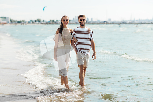 Image of happy couple walking along summer beach