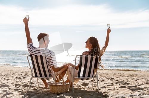 Image of happy couple drinking champagne on summer beach