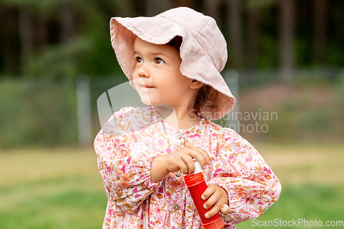 Image of happy baby girl with soap bubble blower in summer