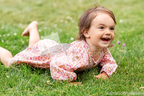 Image of happy little baby girl lying on grass in summer