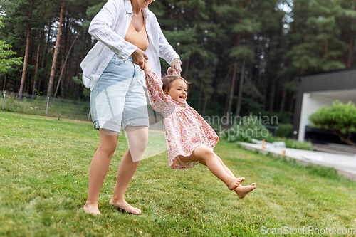 Image of happy mother playing with baby daughter outdoors