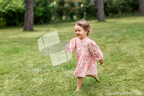 Image of happy little baby girl running across summer field