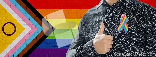 Image of close up of man with gay pride ribbon shows thumb