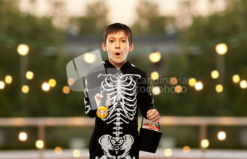 Image of boy in halloween costume with candies and torch