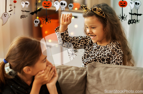 Image of girls in halloween costumes playing with spider