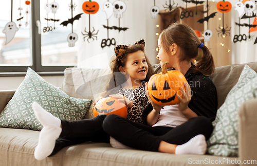 Image of girls in halloween costumes with pumpkins at home