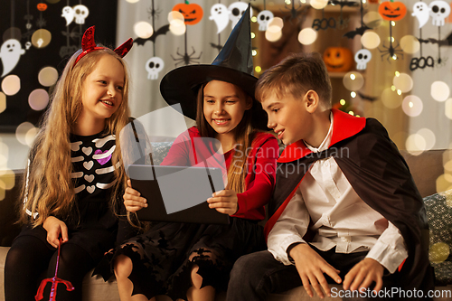 Image of kids in halloween costumes with tablet pc at home