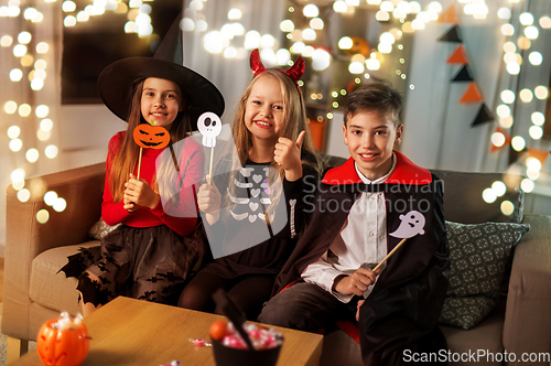 Image of kids in halloween costumes having fun at home