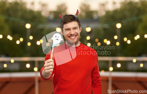 Image of happy man in halloween costume of devil over grey