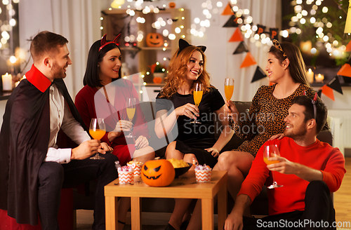 Image of happy friends in halloween costumes at home party