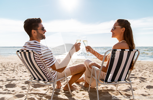 Image of happy couple drinking champagne on summer beach