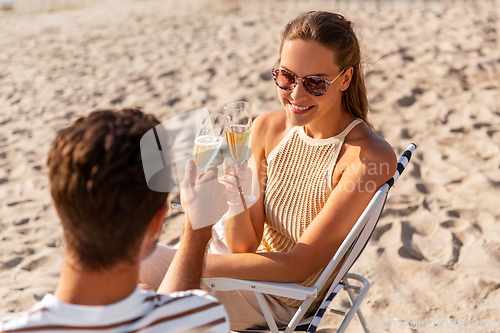 Image of happy couple drinking champagne on summer beach