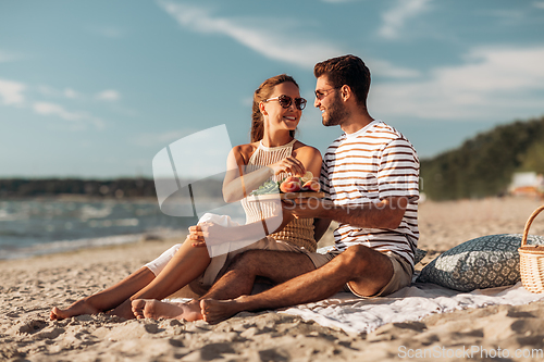 Image of happy couple with food having picnic on beach