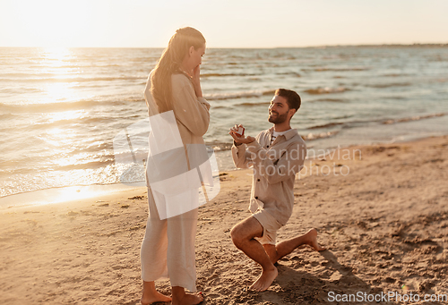 Image of man with ring making proposal to woman on beach