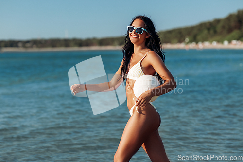 Image of woman in bikini posing with volleyball on beach