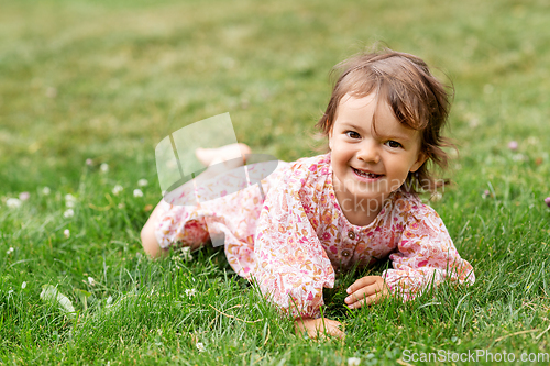 Image of happy little baby girl lying on grass in summer