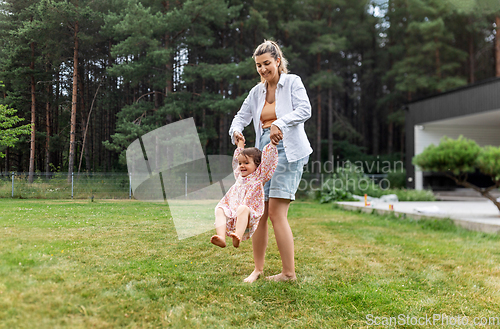 Image of happy mother playing with baby daughter outdoors