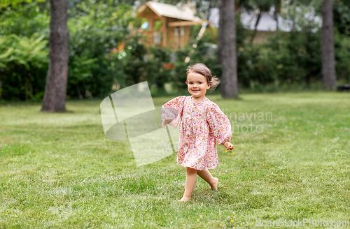 Image of happy little baby girl running across summer field