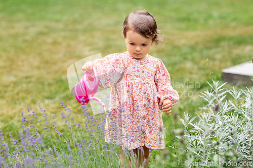 Image of happy baby girl with watering can in summer garden